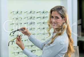 Smiling female customer selecting spectacles