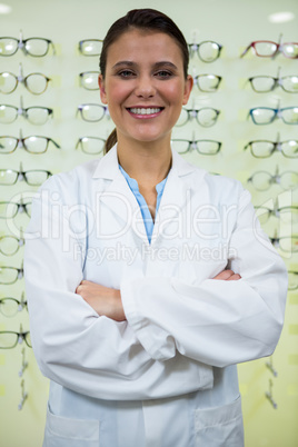 Optometrist standing with arms crossed in optical store