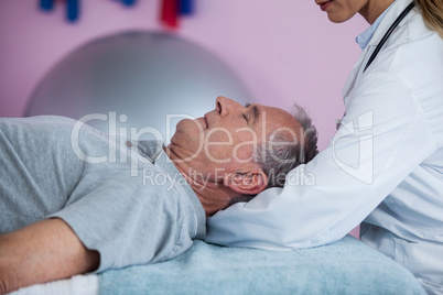 Senior man receiving neck massage from physiotherapist