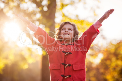 Happy girl standing against autumn tree at park