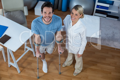 Physiotherapist helping patient to walk with crutches