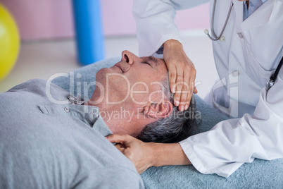 Senior man receiving neck massage from physiotherapist