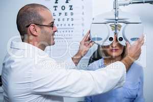 Smiling optometrist examining female patient on phoropter