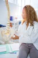 Smiling physiotherapist holding a spine model