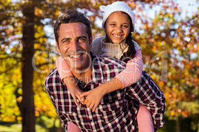 Father piggybacking daughter at park