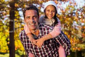 Father piggybacking daughter at park