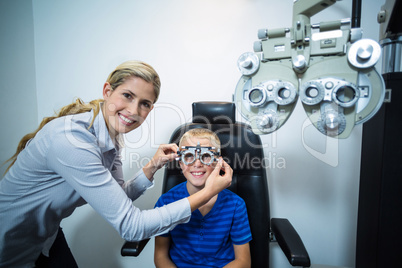 Female optometrist examining young patient with phoropter