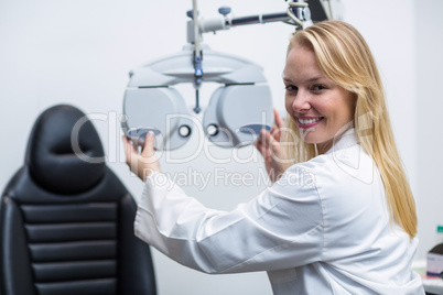 Smiling female optometrist adjusting phoropter