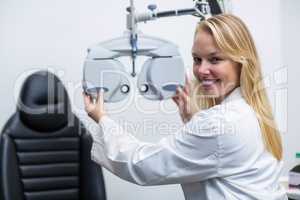 Smiling female optometrist adjusting phoropter