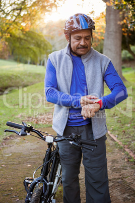 Man touching his watch next to his bike