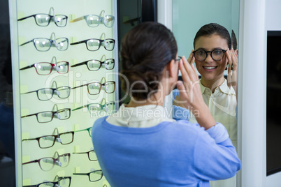 Female customer wearing spectacles and checking in mirror
