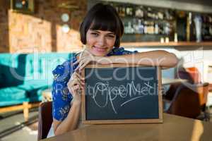 Smiling woman sitting in the coffee shop with a open sign