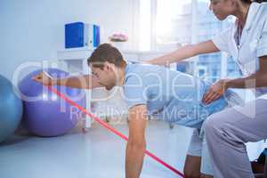 Female physiotherapist assisting a male patient while exercising