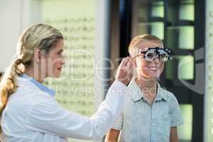 Female optometrist examining young patient with phoropter