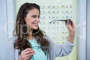 Female customer choosing spectacles in optical store
