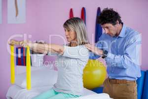 Senior woman training with exercise band assisted by physiothera