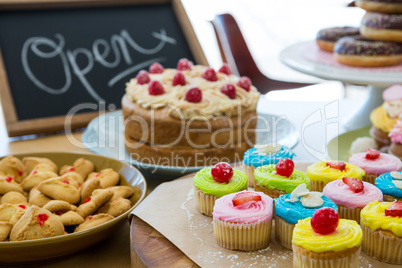 Close-up of various sweet foods on table with open signboard