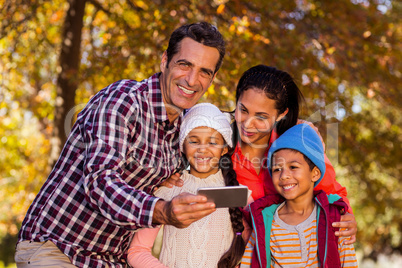 Man holding mobile phone with family at park