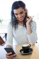 Woman using mobile phone and a coffee cup on the table in coffee