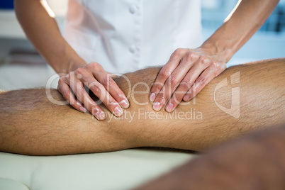 Mid section of physiotherapist giving leg massage to a patient