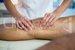 Mid section of physiotherapist giving leg massage to a patient