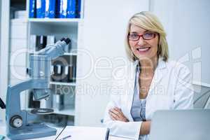 Smiling optometrist sitting with arms crossed