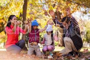 Cheerful family playing with autumn leaves