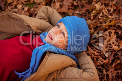 High angle view of thoughtful boy lying at park during autumn