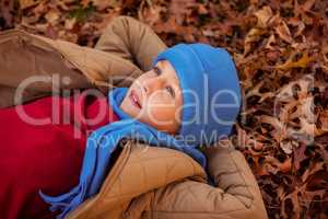 High angle view of thoughtful boy lying at park during autumn