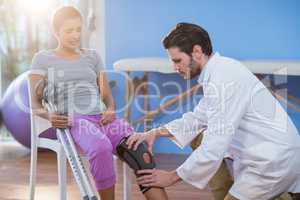 Physiotherapist examining female patients knee