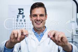 Smiling optometrist holding spectacles