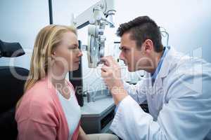Optometrist examining female patient on phoropter