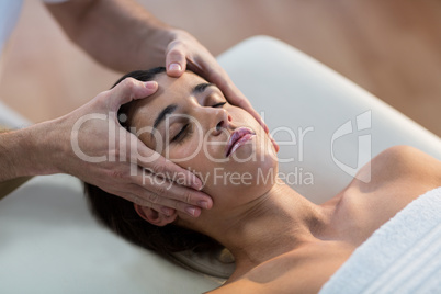 Male physiotherapist giving head massage to female patient