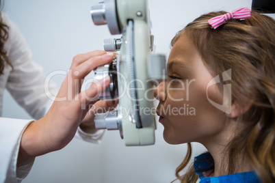 Female optometrist examining young patient on phoropter