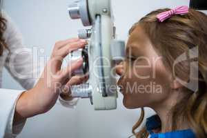 Female optometrist examining young patient on phoropter