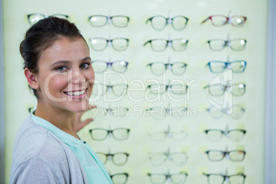 Smiling female customer standing in optical store