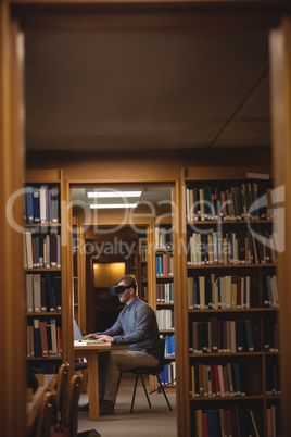 Mature student in virtual reality headset using laptop