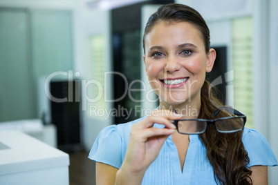 Female customer holding spectacles in optical store