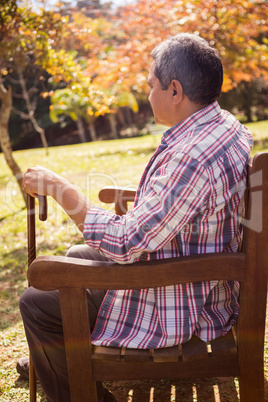 Elderly man sitting on bench with his cane