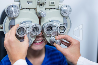 Young patient under going eye test through phoropter