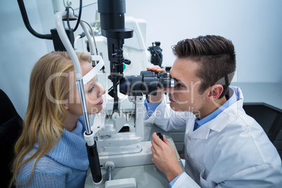 Optometrist examining female patient on slit lamp