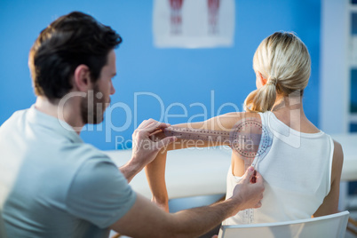 Male therapist measuring female patient shoulder with goniometer