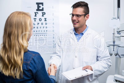 Optometrist shaking hands with female patient