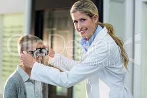 Female optometrist examining young patient with phoropter
