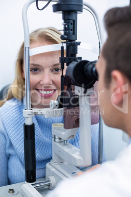 Optometrist examining female patient on slit lamp