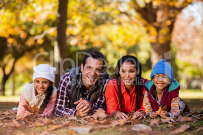 Portrait of cheerful family lying on field during autumn