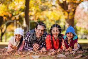 Portrait of cheerful family lying on field during autumn