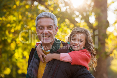 Father piggybacking daughter at park