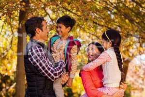 Happy parents carrying children at park