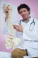 Portrait of physiotherapist sitting with spine model